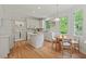 Bright, white kitchen with island, stainless appliances, hardwood floors, and eat-in table with window views at 4900 American Dr, Durham, NC 27705