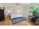 Bright main bedroom featuring a ceiling fan, sitting area, and a large window with view of surrounding trees at 4900 American Dr, Durham, NC 27705
