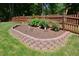 Beautifully landscaped flower bed with brick border and decorative elements in the backyard at 5 Burgess Ct, Hillsborough, NC 27278