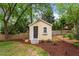 Quaint backyard shed with a dark door and a small window box surrounded by trees at 5709 Lakehaven Dr, Raleigh, NC 27612