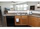 Kitchen featuring granite countertops, black dishwasher, and wood cabinets adjacent to a sunlit living space at 621 Childsberg Way, Hillsborough, NC 27278