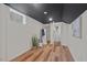 Finished basement featuring wood-look floors, white walls, and a sleek black ceiling, with a view into the bathroom at 623 Massey Ave, Durham, NC 27701