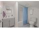 Well-lit bathroom featuring gray vanity, shower/tub with blue curtain, and modern toilet at 623 Massey Ave, Durham, NC 27701