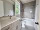 Bathroom featuring vanity with drawers, a mirror, a bathtub with gray tile surround, and a toilet at 629 Conover Rd, Durham, NC 27703