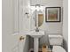 Stylish half bathroom features a pedestal sink, decorative mirror, and modern fixtures at 6509 Virgilia Ct, Raleigh, NC 27616