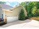 A side garage view with a white garage door and lush landscaping at 67 Crimson Way, Pittsboro, NC 27312