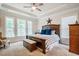 Bright main bedroom with a tray ceiling, large windows, and an upholstered bench at the foot of the bed at 67 Crimson Way, Pittsboro, NC 27312