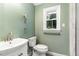 Bathroom featuring white vanity, sink, toilet, accessible grab bars, and a window for natural lighting at 6820 Chamonix Pl, Raleigh, NC 27613