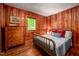 Charming bedroom with wood-paneled walls, hardwood floors, and a cozy bed with decorative pillows at 7723 Johnson Mill Rd, Bahama, NC 27503