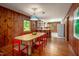Dining room with wood paneling, hardwood floors, and views into the open kitchen at 7723 Johnson Mill Rd, Bahama, NC 27503