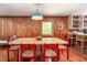 Dining room with wood paneling, hardwood floors, and an open view into the kitchen at 7723 Johnson Mill Rd, Bahama, NC 27503