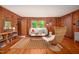 Bright living room with wood-paneled walls, hardwood floors, and a modern rug and wicker chair at 7723 Johnson Mill Rd, Bahama, NC 27503
