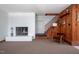 Spacious living room with a fireplace, stairs, and wood-paneled walls for a cozy feel at 7723 Johnson Mill Rd, Bahama, NC 27503