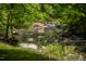 Picturesque view of a stream flowing through rocks and lush greenery, creating a serene setting at 7723 Johnson Mill Rd, Bahama, NC 27503