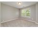 Bright bedroom with neutral tones, carpeted floors, and a window offering a view at 809 Amarillo Rose Ln, Durham, NC 27712