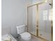 Bathroom with a white toilet and shower enclosed by glass doors with gold trim at 815 Carpenter Town Ln, Cary, NC 27519