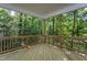 A covered deck features wooden flooring and overlooks a tranquil wooded area, perfect for outdoor relaxation at Lot 3260 Yorkshire Cir, Sanford, NC 27332