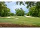 Scenic golf course with sand traps, green grass, trees, and water in the background, partly shaded by trees at Lot 3260 Yorkshire Cir, Sanford, NC 27332