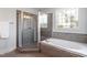 Luxurious bathroom featuring a glass-enclosed shower, separate tub with tile surround, and a patterned window at 10 Princeton Manor Dr, Youngsville, NC 27596