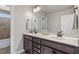 Bathroom features dual dark wood vanities, white countertops, mirrors, and tiled shower and flooring at 10 Princeton Manor Dr, Youngsville, NC 27596