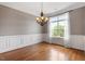 Formal dining room with hardwood floors, a chandelier, and wainscoting beneath a large window at 10 Princeton Manor Dr, Youngsville, NC 27596