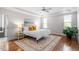 Main bedroom with tray ceiling, hardwood floors, a decorative rug, and a seating area by the windows at 10 Princeton Manor Dr, Youngsville, NC 27596