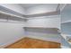 Walk-in closet featuring hardwood floors, custom shelving, and hanging rods for organized storage at 10 Princeton Manor Dr, Youngsville, NC 27596