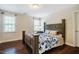 Bedroom with hardwood floors, two windows, and a dark wood bed with a blue flower comforter at 100 Panoramic Ct, Cary, NC 27519