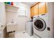 Practical laundry room with a utility sink, washer, and dryer, plus extra storage with wall-mounted shelving at 100 Panoramic Ct, Cary, NC 27519
