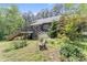 Backyard with lush greenery, featuring a wooden deck, steps, and a bench surrounded by flowers and trees at 1000 Phils Creek Rd, Chapel Hill, NC 27516