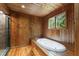 A wood paneled bathroom shows a white hot tub surrounded by wood planks and a dark tiled shower at 1000 Phils Creek Rd, Chapel Hill, NC 27516
