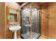 The wood-paneled bathroom has a tiled stand-up shower, a pedestal sink and a framed mirror at 1000 Phils Creek Rd, Chapel Hill, NC 27516