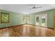 Spacious bedroom featuring hardwood floors, neutral walls, a ceiling fan, and double doors leading to the outside at 1000 Phils Creek Rd, Chapel Hill, NC 27516