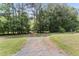 Wide gravel driveway surrounded by lush greenery provides access to the property at 1000 Phils Creek Rd, Chapel Hill, NC 27516