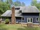 Rear exterior of home with blue siding, brick chimney, deck, and outdoor access at 1000 Phils Creek Rd, Chapel Hill, NC 27516