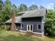 Rear exterior view of two-story home featuring a brick chimney, white trim windows, and access to backyard at 1000 Phils Creek Rd, Chapel Hill, NC 27516