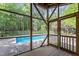 Screened-in porch view of the outdoor pool with blue water surrounded by lush greenery and a concrete patio at 1000 Phils Creek Rd, Chapel Hill, NC 27516