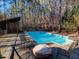 Backyard pool with chairs and firepit surrounded by a wooded area at 1000 Phils Creek Rd, Chapel Hill, NC 27516
