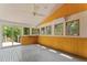 Bright sunroom with wood-paneled walls, multiple windows, and a sliding glass door to the outside deck at 1000 Phils Creek Rd, Chapel Hill, NC 27516