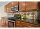Close up of kitchen featuring stainless steel stove, granite countertops, wood cabinets, and tile backsplash at 1103 Weston Green Loop, Cary, NC 27513