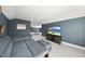 Spacious upstairs game room featuring gray-blue walls, plush seating, and bright windows at 113 Amberwing Ct, Holly Springs, NC 27540