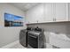 Well-equipped laundry room featuring modern washer and dryer, ample cabinet space, and utility sink at 113 Amberwing Ct, Holly Springs, NC 27540