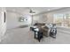 Bright living room with gray walls, plush carpet, ceiling fan, and large windows for natural light at 113 Amberwing Ct, Holly Springs, NC 27540