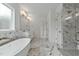 Luxurious bathroom with double sinks, a soaking tub, glass shower, and marble-patterned tile at 1218 Red Cedar Ct, Youngsville, NC 27596