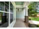 Covered front porch with brick columns, a hanging lantern, and a view of the lush landscape at 1218 Red Cedar Ct, Youngsville, NC 27596