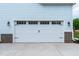 A white garage door features carriage accents, complementing the blue siding and brick detail of the home's exterior at 1218 Red Cedar Ct, Youngsville, NC 27596
