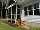 Inviting screened porch with wood steps, black railings, and bright windows offering a tranquil retreat at 1218 Red Cedar Ct, Youngsville, NC 27596