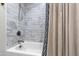Clean white tub and shower combination featuring stylish tilework and neutral shower curtain at 1305 Kimberly Dr, Raleigh, NC 27609