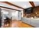 Open kitchen layout with wood floors, beams, gray cabinets, brick accents, and an adjacent eating area at 1305 Kimberly Dr, Raleigh, NC 27609