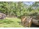 Wooden deck with seating overlooks a spacious backyard and lush green trees, providing a tranquil outdoor space at 1307 Arnette Ave, Durham, NC 27707